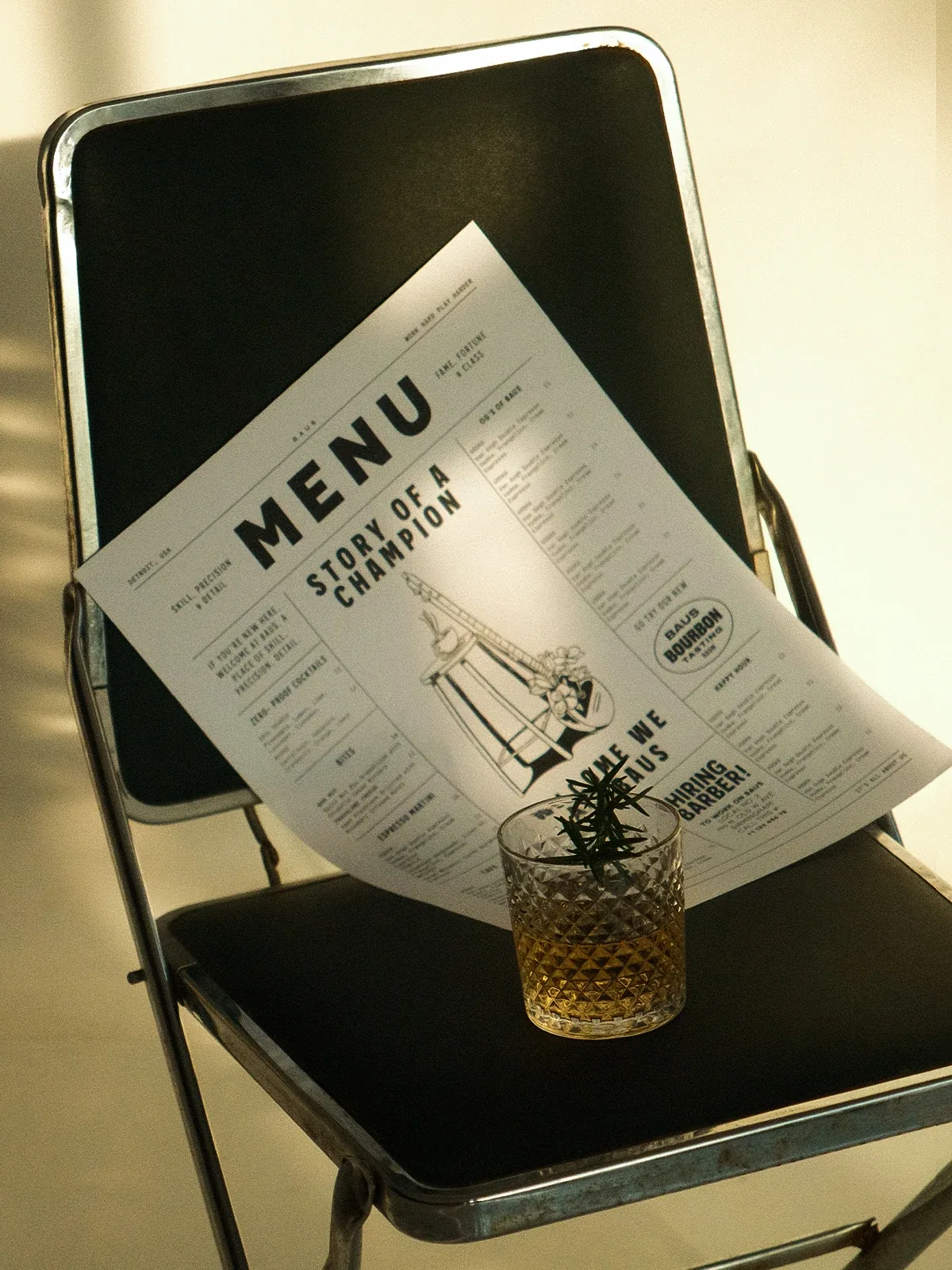 Baus bar menu with illustrated cover on a chair next to a cocktail