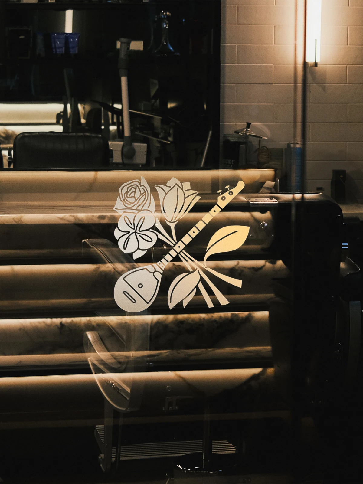 Baus floral emblem in white on dark glass inside the barbershop