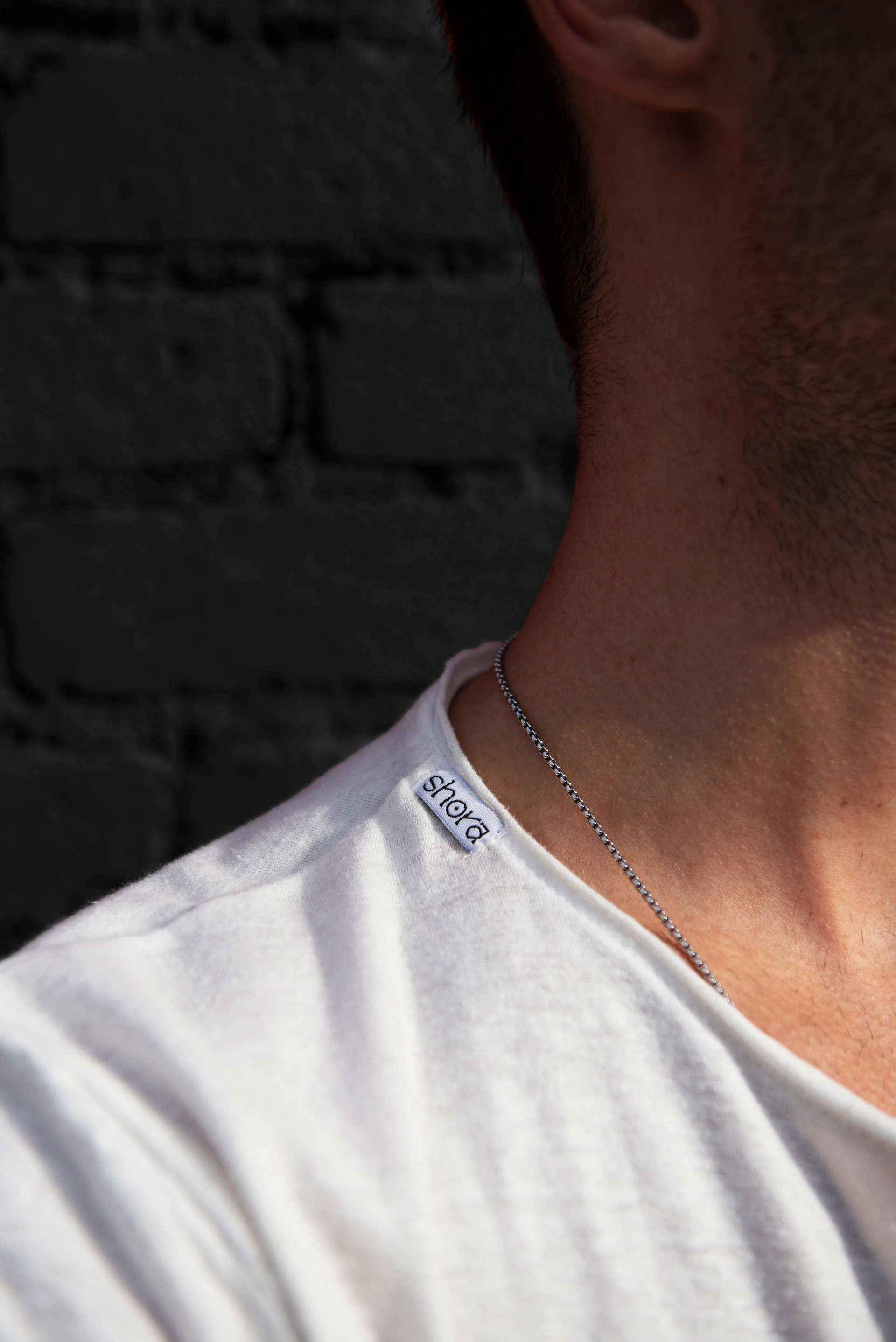 Man wearing a white Shora T-shirt with woven neck label